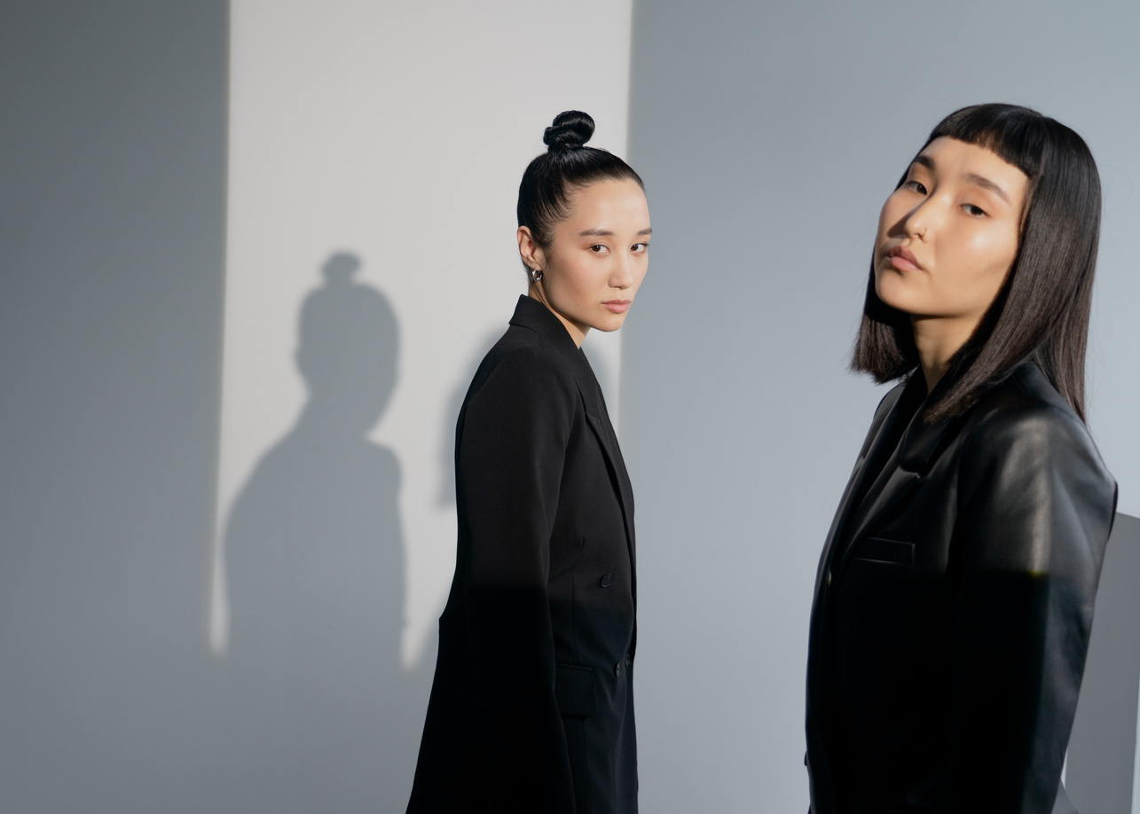 Two Women Standing Near White Wall